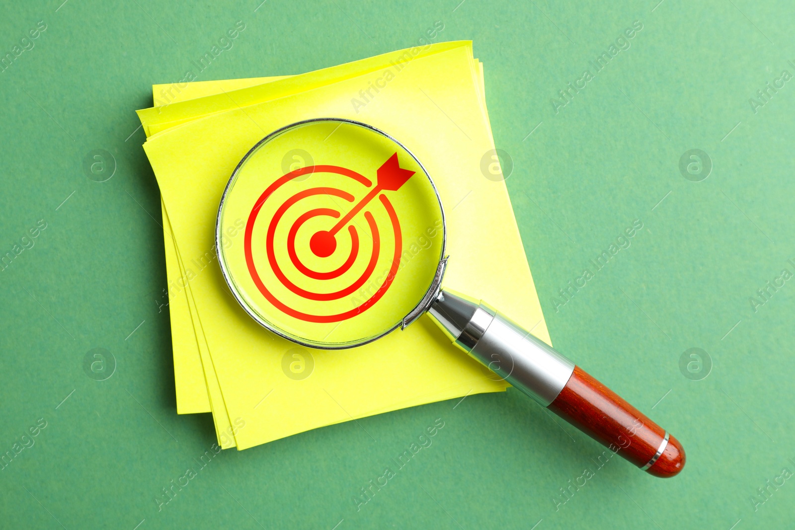 Targeting. Paper note with bullseye and magnifying glass on green background, top view Image of Targeting. Paper note with bullseye and magnifying glass on green background, top view