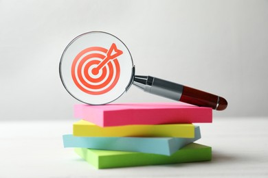 Image of Targeting. Magnifying glass with bullseye inside and paper notes on table