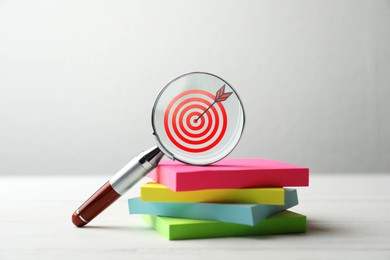 Image of Targeting. Magnifying glass with bullseye inside and paper notes on table