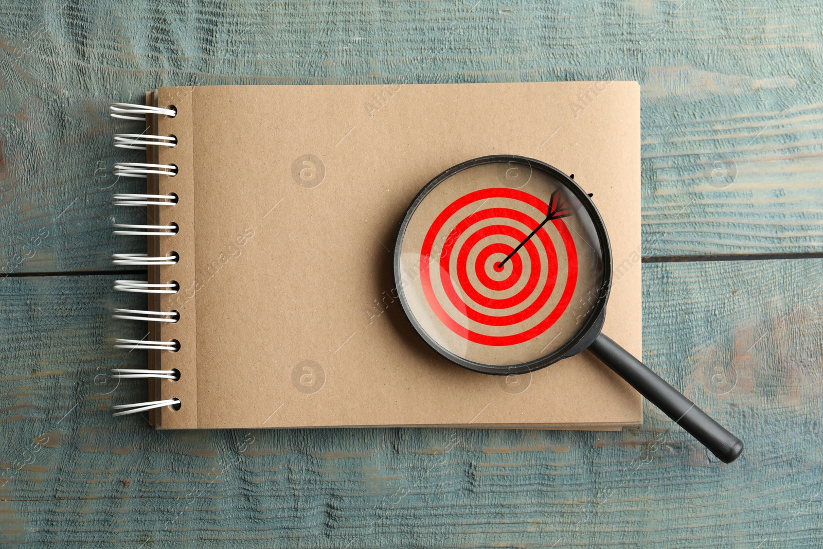 Targeting. Notebook with bullseye and magnifying glass on wooden background, top view Image of Targeting. Notebook with bullseye and magnifying glass on wooden background, top view