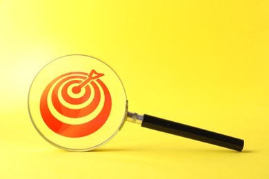 Image of Targeting. Magnifying glass with bullseye inside on yellow background, space for text