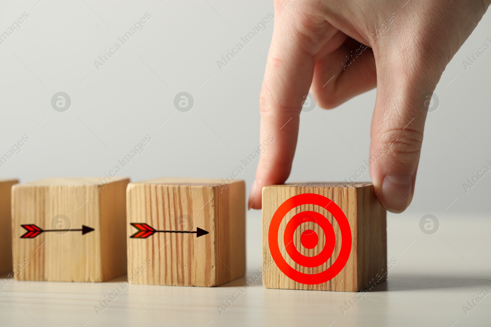 Targeting. Woman putting wooden cube on table, closeup. Cubes with arrows pointing at one with bullseye Image of Targeting. Woman putting wooden cube on table, closeup. Cubes with arrows pointing at one with bullseye