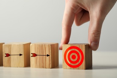 Image of Targeting. Woman putting wooden cube on table, closeup. Cubes with arrows pointing at one with bullseye