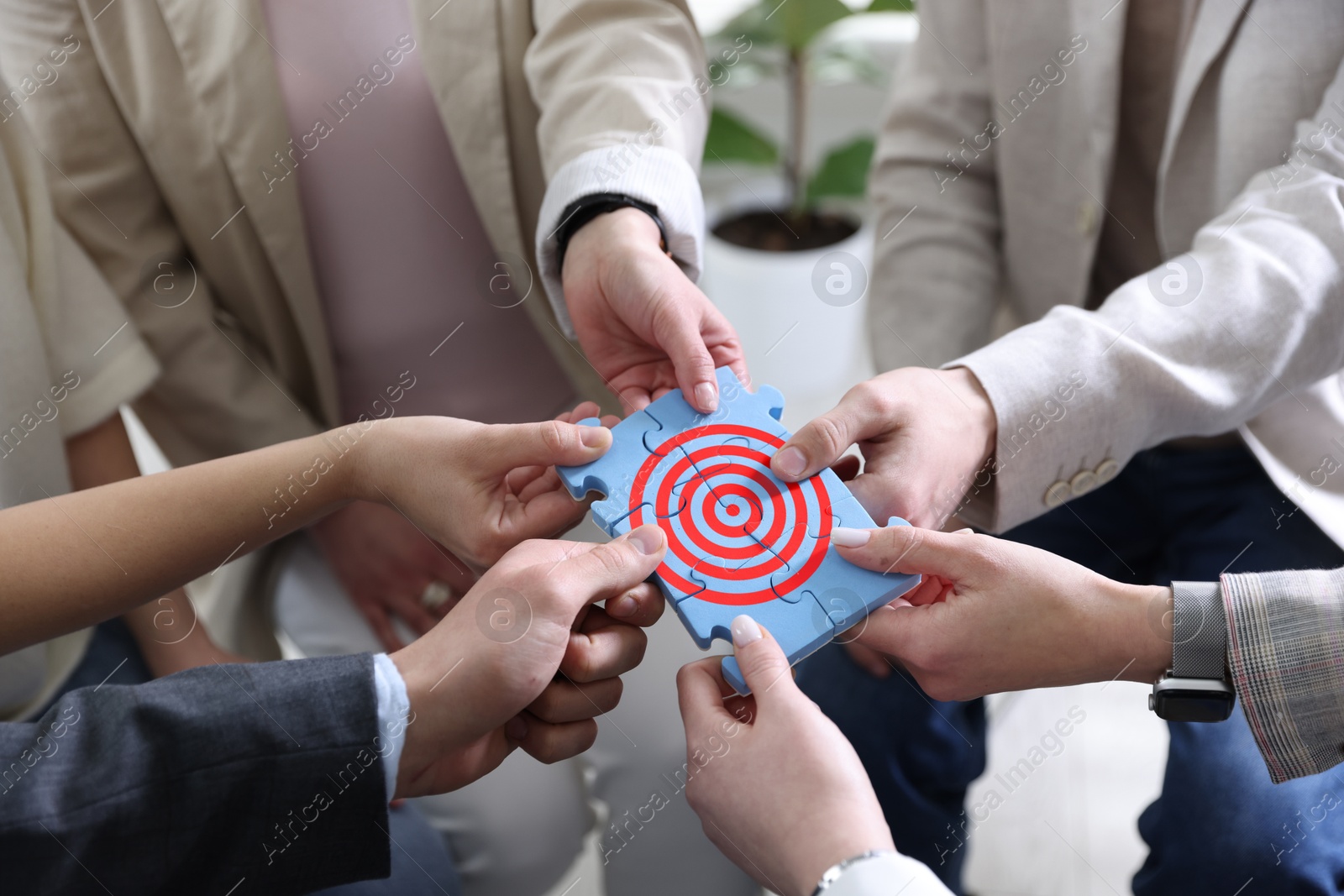 Targeting. People holding puzzle pieces together to make image of bullseye, closeup Image of Targeting. People holding puzzle pieces together to make image of bullseye, closeup