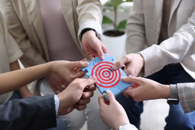Image of Targeting. People holding puzzle pieces together to make image of bullseye, closeup