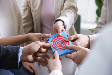 Image of Targeting. People holding puzzle pieces together to make image of bullseye, closeup