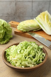 Photo of Fresh Chinese cabbages and knife on wooden table, closeup