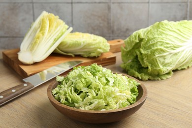 Photo of Fresh Chinese cabbages and knife on wooden table, closeup