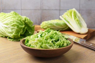 Photo of Fresh Chinese cabbages and knife on wooden table, closeup
