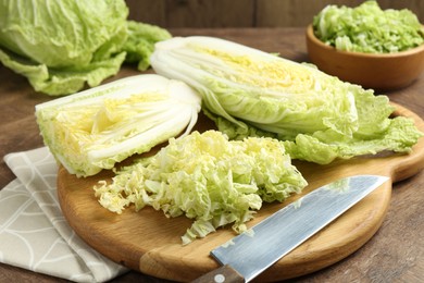 Photo of Fresh Chinese cabbages and knife on wooden table, closeup