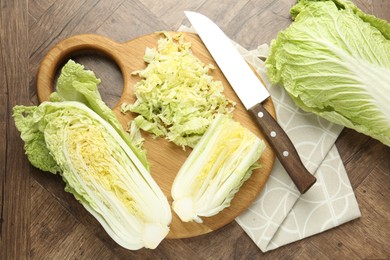 Photo of Fresh Chinese cabbages and knife on wooden table, flat lay