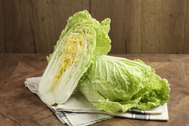 Photo of Whole and cut Chinese cabbages on wooden table