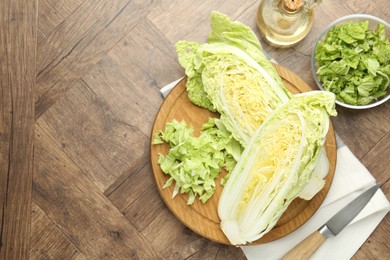 Photo of Fresh cut Chinese cabbage, oil and knife on wooden table, flat lay. Space for text