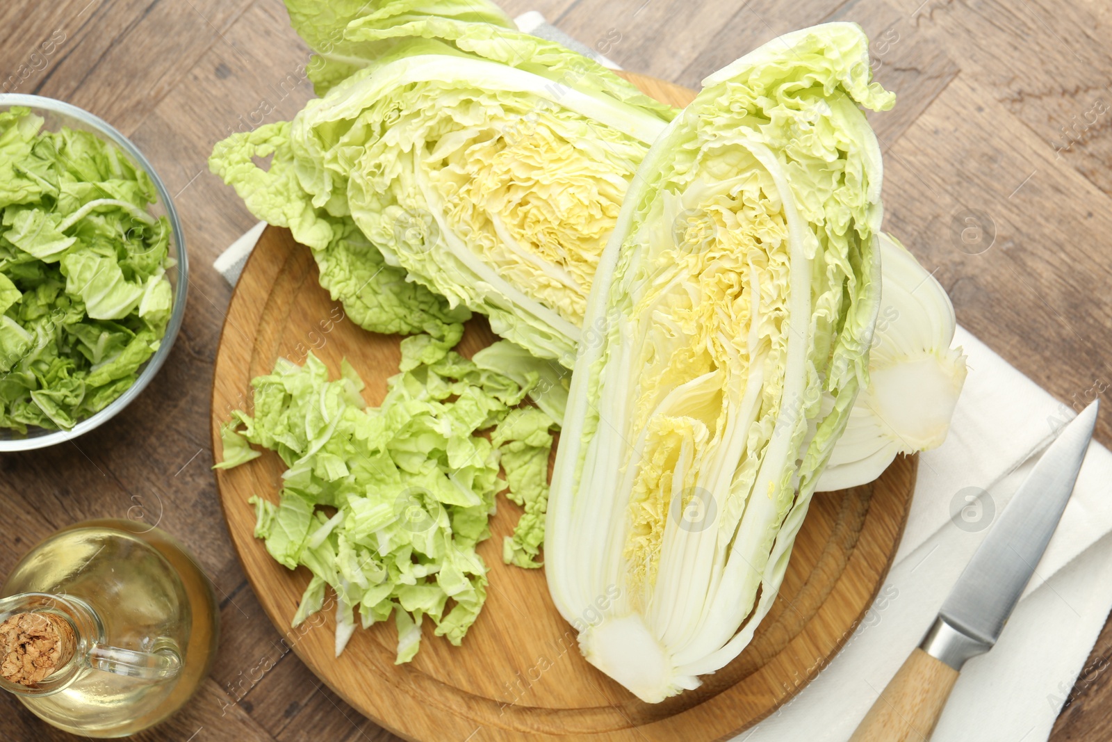 Fresh cut Chinese cabbage, oil and knife on wooden table, flat lay Photo of Fresh cut Chinese cabbage, oil and knife on wooden table, flat lay
