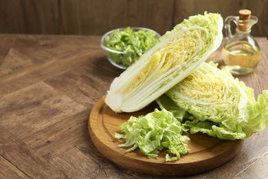 Photo of Fresh cut Chinese cabbage and oil on wooden table, space for text