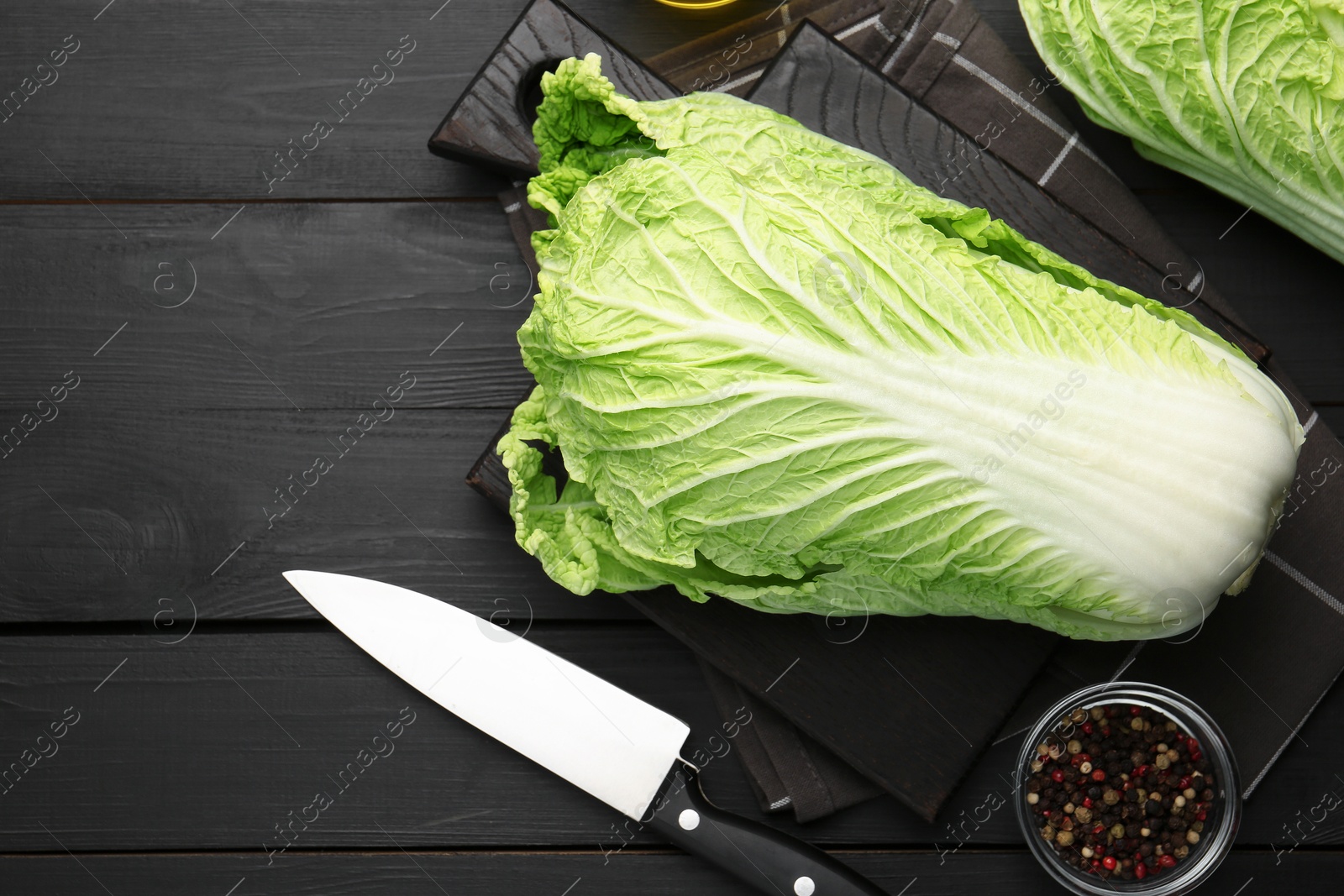 Fresh Chinese cabbages, knife and peppercorns on black wooden table, flat lay Photo of Fresh Chinese cabbages, knife and peppercorns on black wooden table, flat lay