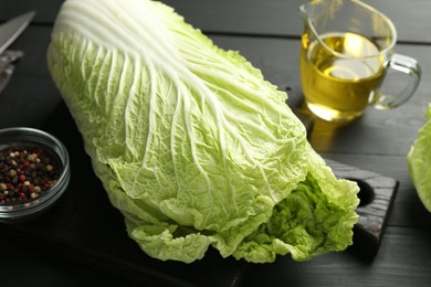 Photo of Fresh Chinese cabbage, oil and peppercorns on black wooden table, closeup