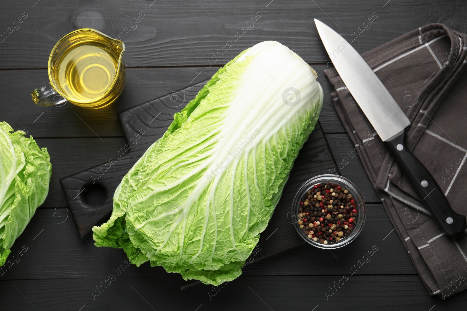 Fresh Chinese cabbages, oil, knife and peppercorns on black wooden table, flat lay Photo of Fresh Chinese cabbages, oil, knife and peppercorns on black wooden table, flat lay