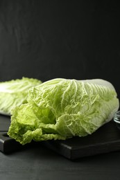 Photo of Fresh Chinese cabbages on black wooden table, closeup. Space for text