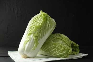 Photo of Fresh Chinese cabbages on black wooden table