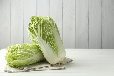 Photo of Fresh Chinese cabbages on white wooden table, space for text