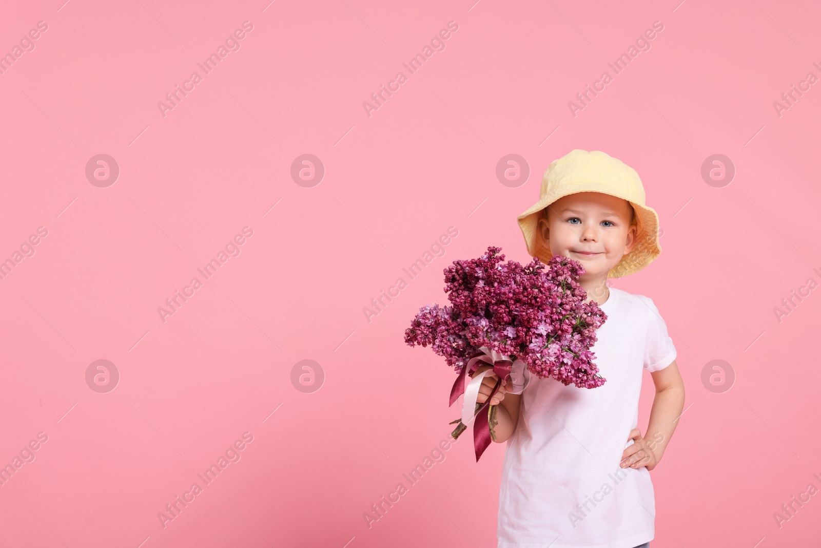 Little boy with bouquet of lilac flowers on pink background, space for text Photo of Little boy with bouquet of lilac flowers on pink background, space for text