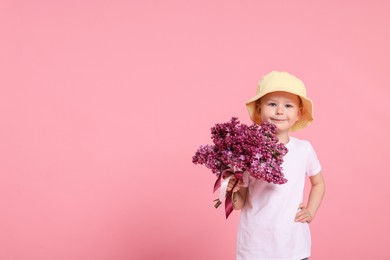 Photo of Little boy with bouquet of lilac flowers on pink background, space for text