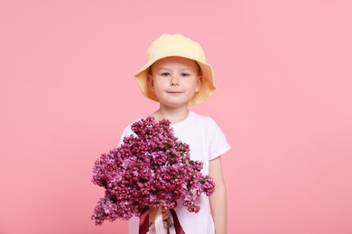Photo of Little boy with bouquet of lilac flowers on pink background
