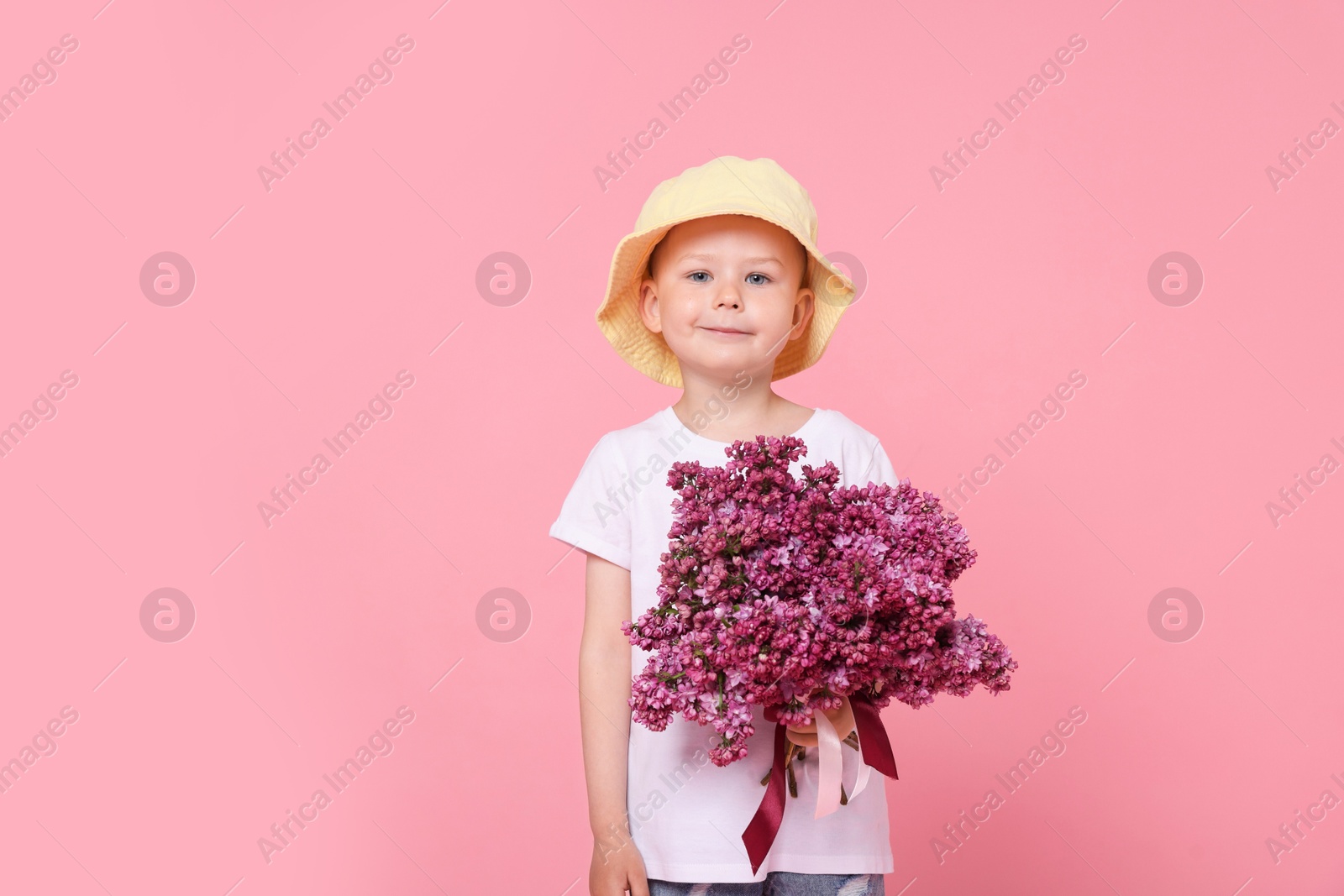 Little boy with bouquet of lilac flowers on pink background Photo of Little boy with bouquet of lilac flowers on pink background