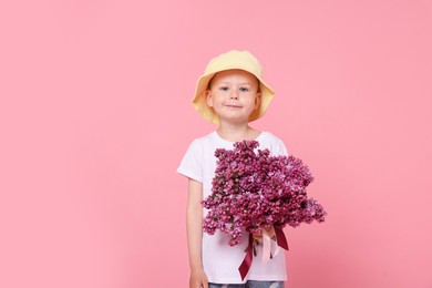 Photo of Little boy with bouquet of lilac flowers on pink background