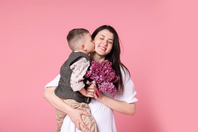 Photo of Mother and her son with bouquet of lilac flowers on pink background