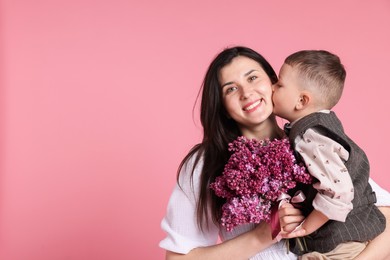 Photo of Mother and her son with bouquet of lilac flowers on pink background, space for text