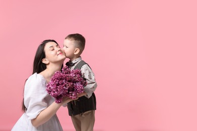 Photo of Mother and her son with bouquet of lilac flowers on pink background, space for text