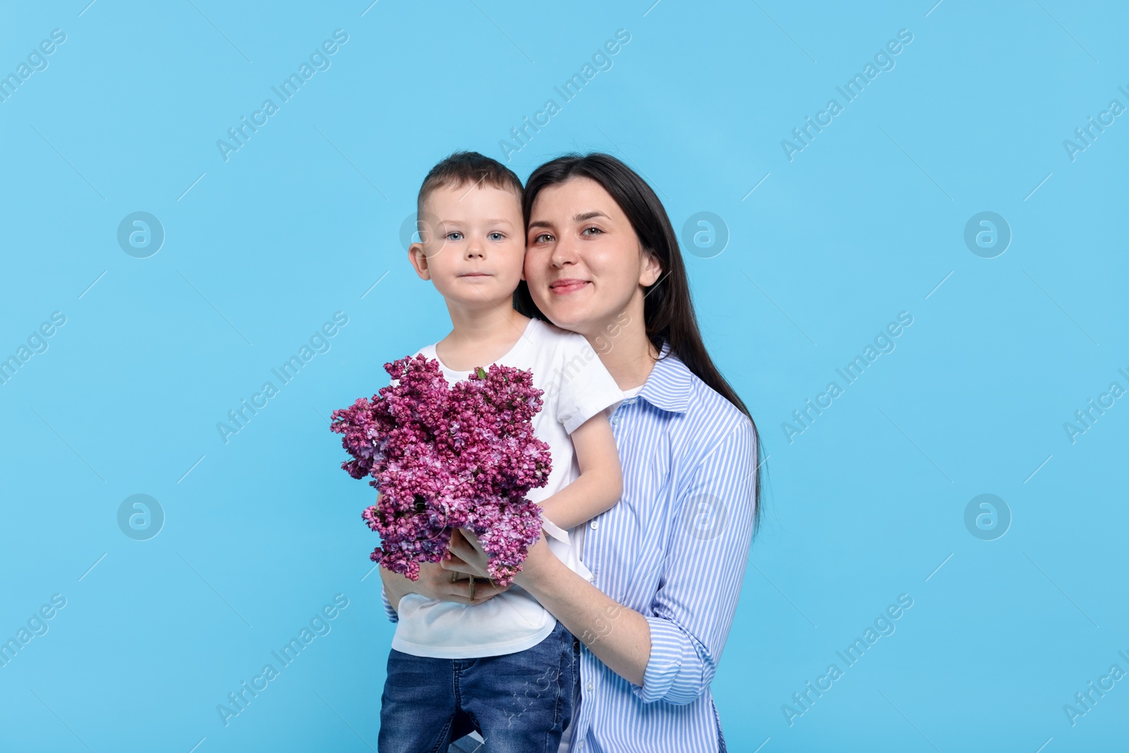 Mother and her son with bouquet of lilac flowers on light blue background Photo of Mother and her son with bouquet of lilac flowers on light blue background