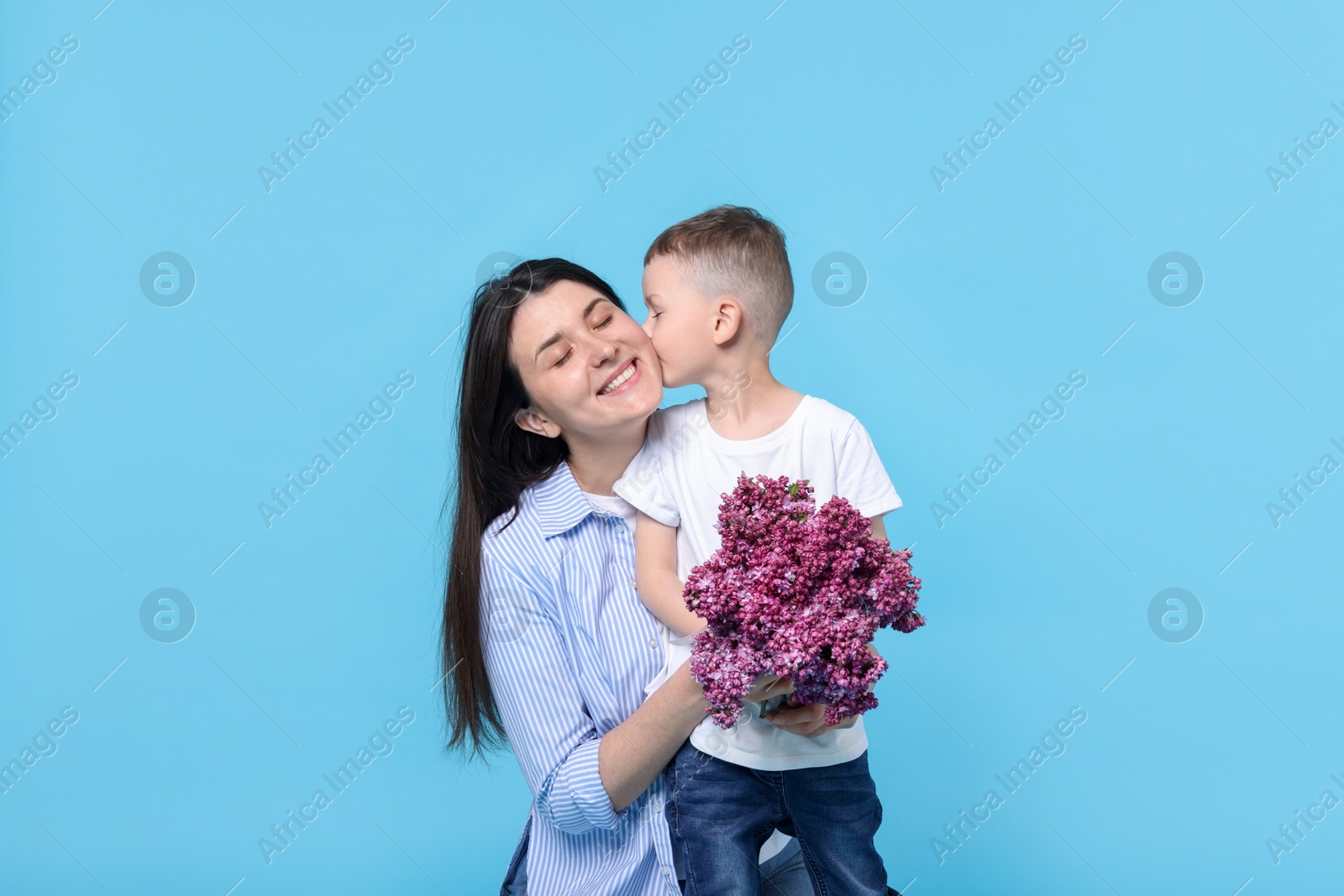 Mother and her son with bouquet of lilac flowers on light blue background Photo of Mother and her son with bouquet of lilac flowers on light blue background