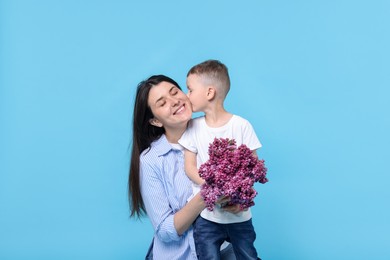 Photo of Mother and her son with bouquet of lilac flowers on light blue background