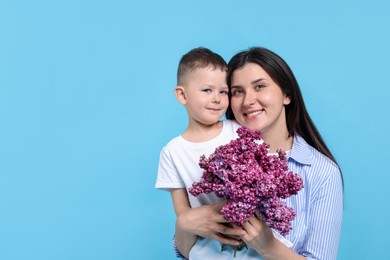 Photo of Mother and her son with bouquet of lilac flowers on light blue background, space for text