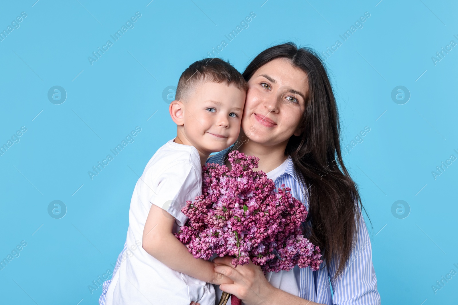 Mother and her son with bouquet of lilac flowers on light blue background Photo of Mother and her son with bouquet of lilac flowers on light blue background