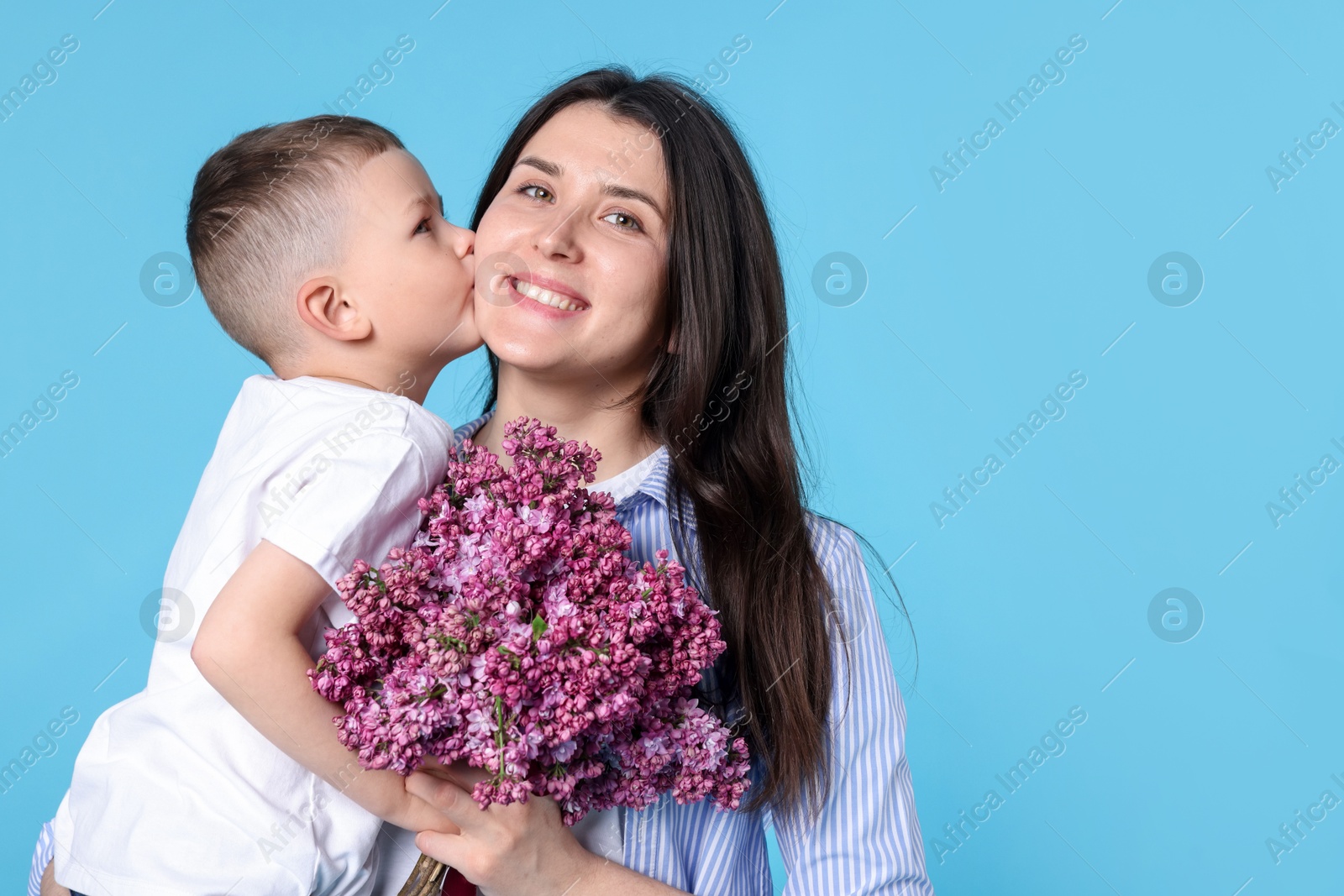 Mother and her son with bouquet of lilac flowers on light blue background, space for text Photo of Mother and her son with bouquet of lilac flowers on light blue background, space for text