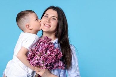 Photo of Mother and her son with bouquet of lilac flowers on light blue background, space for text