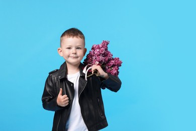 Photo of Little boy with bouquet of lilac flowers showing thumbs up on light blue background, space for text