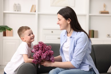 Photo of Mother and her son with bouquet of lilac flowers at home