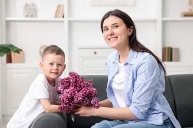 Photo of Mother and her son with bouquet of lilac flowers at home