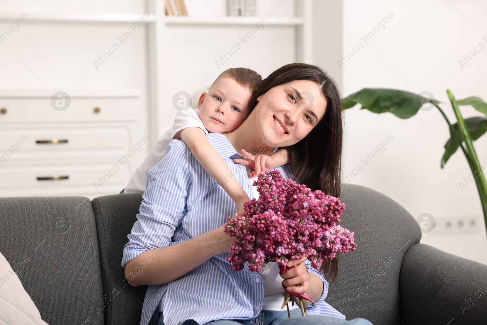 Mother and her son with bouquet of lilac flowers at home Photo of Mother and her son with bouquet of lilac flowers at home