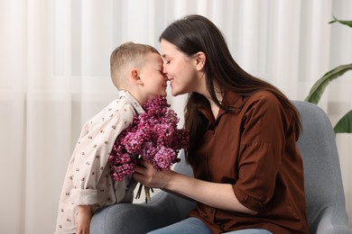 Photo of Mother and her son with bouquet of lilac flowers at home