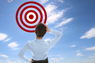 Image of Targeting, goal achievement. Business woman looking at bullseye in sky