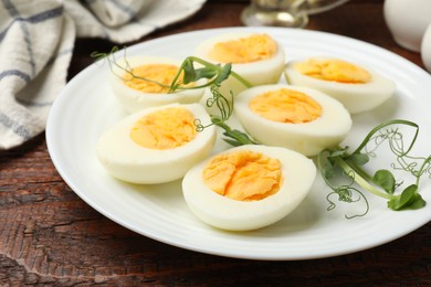 Photo of Boiled eggs and microgreens on wooden table, closeup