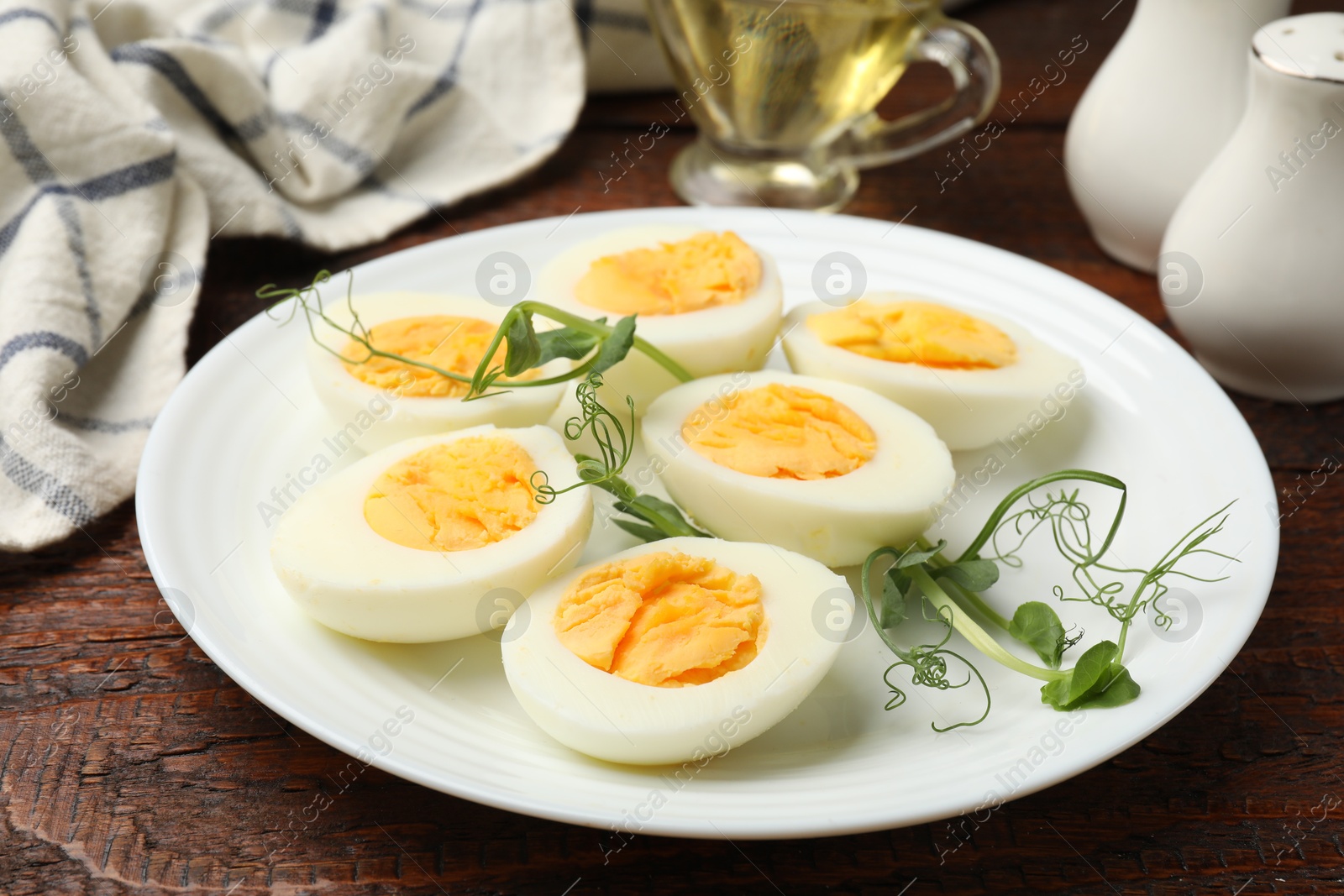 Photo of Boiled eggs and microgreens on wooden table, closeup