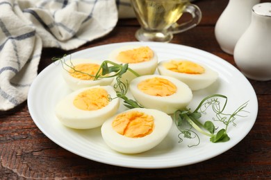 Photo of Boiled eggs and microgreens on wooden table, closeup