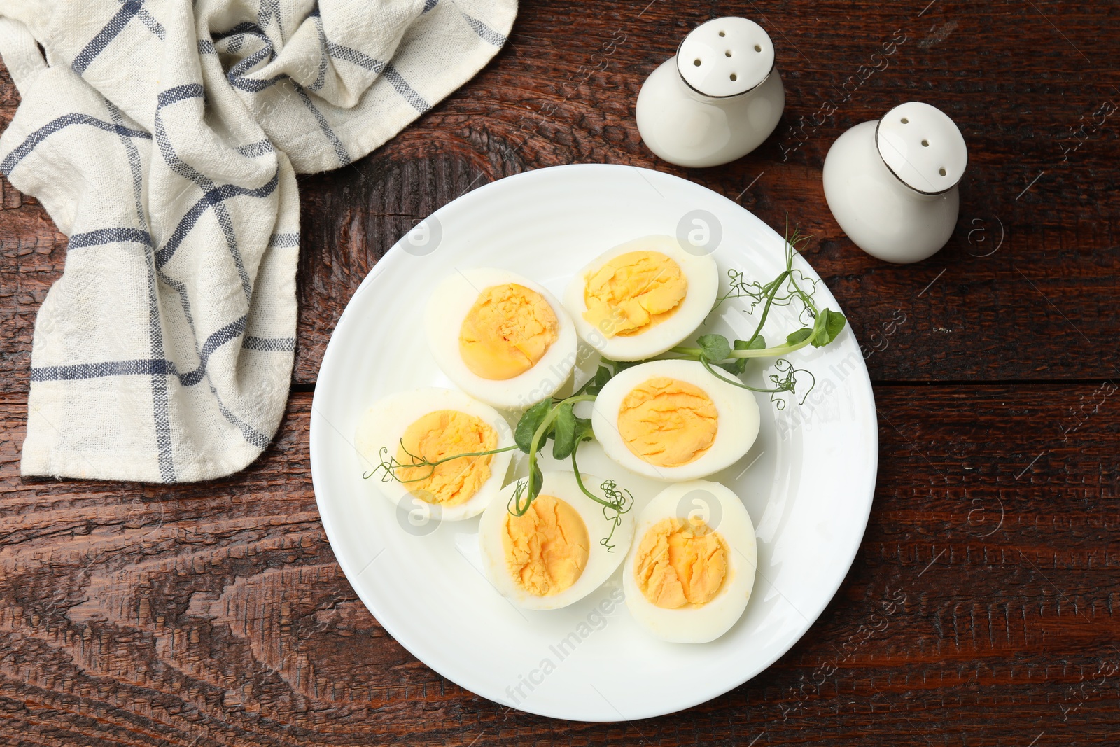 Photo of Boiled eggs and microgreens on wooden table, flat lay